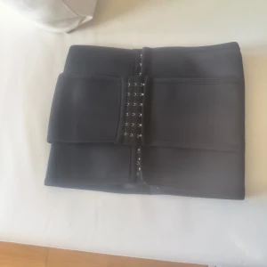 Svart svett midjebälte med hyskor - Snyggt svart midjebälte med hyskor för justering. Perfekt för att ge extra värme och stöd till din träning.. Bältet har en bred design.