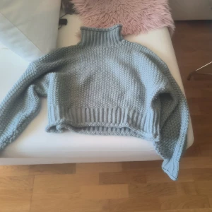 Turkos stickad polotröja från H&M - Säljer en mysig turkos stickad polotröja från H&M. Tröjan har en croppad design med ribbade detaljer vid ärmslut och nederkant. Perfekt för kyliga dagar!