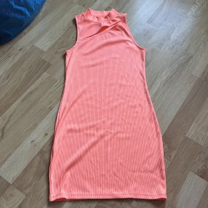 Korallfärgad ribbad klänning från H&M - Snygg korallfärgad klänning från H&M i ribbat material. Den är ärmlös med en hög krage och har en stilren design. Perfekt för en somrig look! 🌸