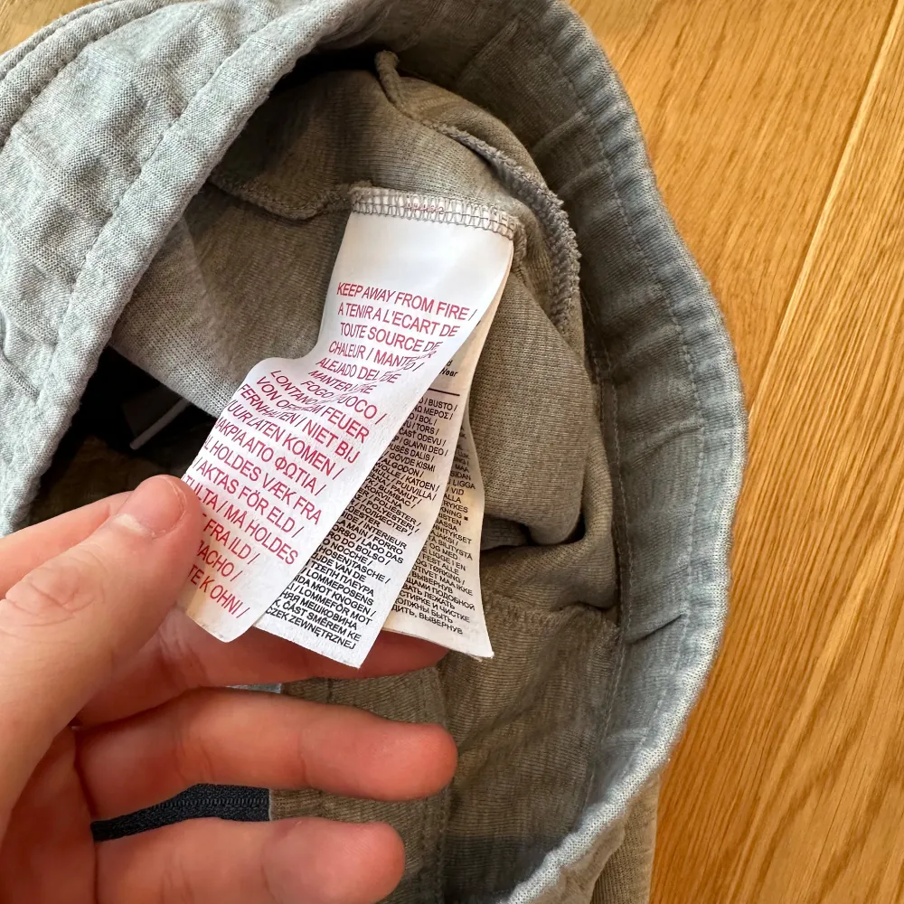 Säljer ett par grå mjukisbyxor från Nike med elastisk midja och dragsko. Byxorna har en avslappnad passform och är perfekta för en chill dag. Nike-loggan är tryckt i svart på sidan.. Farkut & Housut.