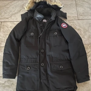 Svart parkajacka från Canada Goose - Mycket fin och otroligt varm jacka. Sparsamt använd. Storlek M. Avtagbar luva! Köpte den ny på NK i STHLM. Nypris ca 18.000kr