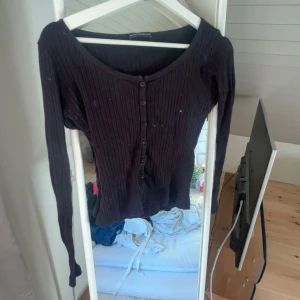 Svart ribbad kofta från brandy Melville  - Svart ribbad kofta med lång ärm och knappar hela vägen framtill. Snygg, smickrande passform med lite djupare halsringning. Perfekt att styla med jeans eller kjol för en chill look.