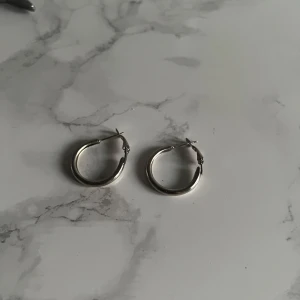 Silvriga hoops örhängen - Snygga silvriga hoops örhängen i klassisk rund form. Perfekta för att ge din look lite extra edge. De har en enkel och stilren design som passar till många olika outfits. Lätta att bära och stängs med smidig låsning.