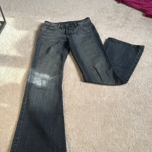 Replay bootcut jeans med broderad logga - Säljer ett par blå bootcut low waist jeans från Replay med coolt broderad Replay-logga baktill. Jeansen har klassisk femficksdesign, kontrastsömmar och ett slitstarkt jeansmaterial. Passformen är loose och de har en snygg tvättad look med ljusa detaljer. Går att diskutera pris💞