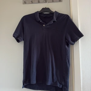  Peak Performance piké - Storleken stämmer inte riktigt skulle säga att den är M-S I storleken. Snygg mörkblå t-shirt från Peak Performance i klassisk pikéstil med krage och två knappar. Diskret broderad logga på bröstet. Tillverkad i mjuk bomull som är skön mot huden. Perfekt för dig som gillar stilrena och sportiga plagg.