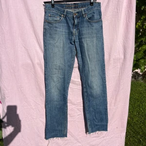 Boomerang Denim Karl blå jeans - Snygga klassiska blå jeans från Boomerang, modell Denim Karl. Jeansen har fem fickor, normal passform med mid-rise i midjan och raka ben. Tillverkade i slitstarkt bomullsjeans med läderpatch bak i midjan. Perfekta till en avslappnad stil. Avklippta längst ner. W33 L33(med avklipp)