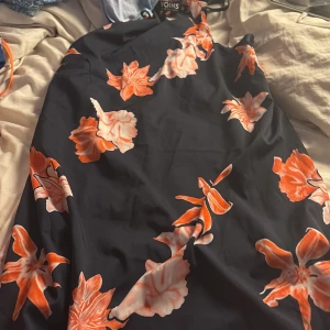 Blommig marinblå klänning från Yoins - Säljer en snygg marinblå klänning från Yoins med stora orangea och vita blommor. Klänningen har ärmlös design och en rak, kort siluett som ger en fräsch vibe. Perfekt för sommarens alla tillfällen och lätt att matcha med accessoarer.