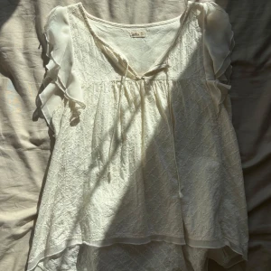 Vit blus med volangärm från Hollister - Supersöt vit blus från Hollister med broderat mönster och volangärmar 