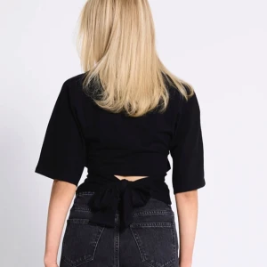 Svart omlottopp med knyt i ryggen - Svart topp med korta ärmar och snygg knytning i ryggen. Aldrig använd säljer en vit också🤗