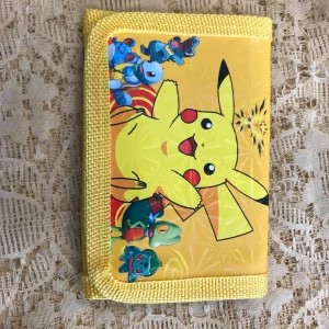 Gul Pokémon plånbok med Pikachu - Säljer en färgglad gul Pokémon plånbok med Pikachu och flera andra karaktärer på framsidan och baksidan. Plånboken har coola tryck och detaljer i gult tyg runt kanterna. Perfekt för dig som vill ha något unikt och lekfullt i fickan. Finns fler kvar 