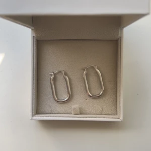 Silvriga rektangulära örhängen - Snygga silvriga örhängen i rektangulär form med mjukt rundade hörn. Går att använda i alla lägen, funkar till allt! Säljer då jag bytt från silversmycken till guldsmycken.