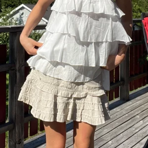 Beige volangkjol med fickor - Supersöt beige kortkjol/ tubetopp beroende på hur man bär den, med flera volanger och två framfickor. Kjolen har dubbla knappar och resår upptill som jag trätt in själv! Materialet är lätt och känns som bomull, perfekt för varma dagar. Köpte på en fransk marknad för 30€ så vet inte vad det är för märke💓💓 Står storlek S men jag skulle mer säga xs-s! (säljer även topparna)