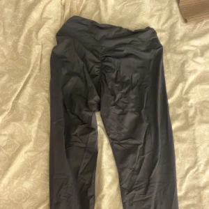 Svarta leggings från ICANIWILL - Säljer ett par svarta leggings från ICANIWILL i storlek M. De har hög midja och snygg scrunch-detalj bak för extra shaping. Materialet är stretchigt och passar perfekt för gymmet eller annan träning. Loggan finns tryckt framtill på höger höft.