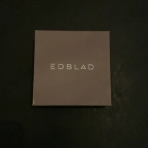 Svart pärlarmband från Edblad - Stilrent svart armband från Edblad med små svarta pärlor och ett snyggt guldfärgat lås. Perfekt accessoar för dig som gillar minimalistisk design och vill ha något som sticker ut lite extra på handleden.