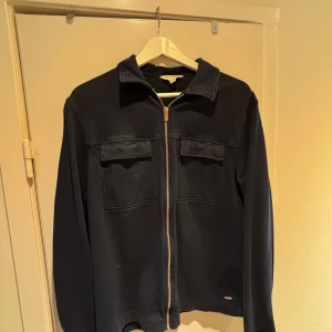 Mörkblå overshirt  - Snygg mörkblå overshirt från Autograph med klassisk krage och två bröstfickor med lock. Jackan har dragkedja framtill och är tillverkad i ett mjukt, strukturerat material som ger en cool och stilren look. Perfekt att slänga på över en t-shirt.
