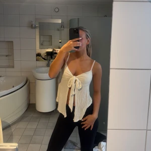 Vit linnetopp med knyt framtill - Säljer en superfin vit linnetopp med smala axelband och snygg knytning framtill. Toppen har en luftig och flowy passform som ger en chill vibe. Perfekt för varma dagar och enkel att styla med jeans eller kjol. Materialet känns mjukt och lätt mot huden.