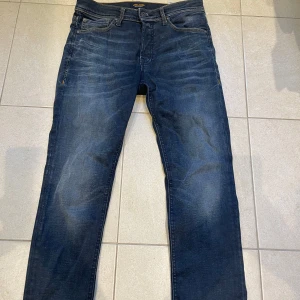 Mörkblå jeans från Jack & Jones - Snygga mörkblå jeans från Jack & Jones med klassisk femficksdesign och subtila slitningar framtill och bak. Jeansen har raka ben och normal passform, tillverkade i slitstarkt denim med skön känsla. Perfekta för dig som gillar en enkel och stilren look.