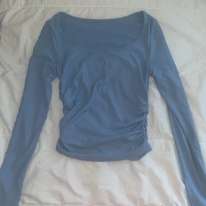 Ljusblå ribbad långärmad topp - Säljer en ljusblå långärmad topp med ribbad struktur och snygg rynkning på sidan. Toppen är i storlek S om jag minns rätt, men funkar även utmärkt som en XS . Perfekt att matcha med jeans eller kjol för en chill och stilren look. Passar även till alla årstider! 