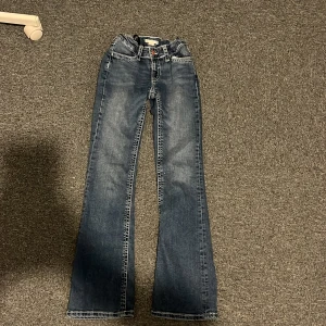 Blå bootcut jeans från Gina Tricot - Snygga blå jeans från Gina Tricot i bootcut-modell med kontrastsömmar och coola fickdetaljer bak. Jag har spänt in dom i midjan därmed ser dom knövliga ut men går att spänna ut!💞