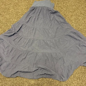 Lång blå volangkjol i bomull - Säljer en snygg långkjol i blått med flera volanger som ger ett flowigt och chill uttryck. Kjolen är gjord i mjuk bomull och har en bred linning upptill för extra komfort. Perfekt för dig som gillar boho-vibe och vill ha något luftigt.