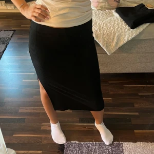 Svart ribbad långkjol från ONLY - Säljer en svart långkjol från ONLY i storlek L. Kjolen är ribbad och har en snygg slits på sidan. Passformen är normal och kjolen är enkel att matcha med olika toppar. Säljer för att den inte kommit till användning❤️