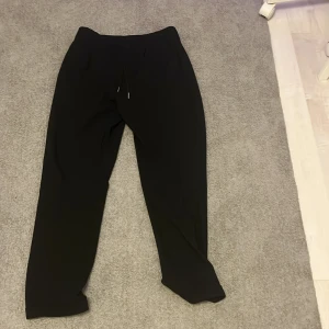 Svarta slim fit mjukisbyxor H&M - Svarta mjukisbyxor från H&M i slim fit-modell med elastisk midja och snörning. Byxorna har en enkel och clean look, perfekta för chill dagar eller när du vill ha det bekvämt. Passar dig som gillar stilrena och smidiga plagg.