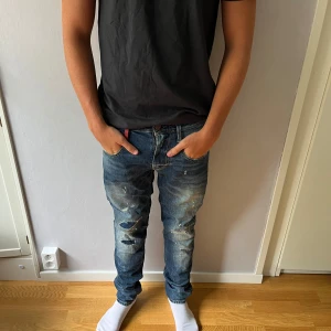 Replay Anbass blå slitna jeans - Säljer ett par Replay Anbass jeans i blå tvätt med coola slitningar och trasiga detaljer på benen. Modellen har normal passform och klassisk femficksdesign. Jeansen har låg midja och är gjorda i mjukt bomullsmaterial med lite stretch för extra komfort.