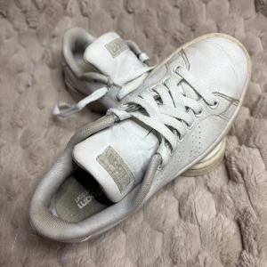 Vita adidas sneakers Cloudfoam stl.35,5  - Fräscha vita adidas sneakers med Cloudfoam Comfort-innersula för extra skön känsla. Klassisk låg modell med snörning, rund tå och perforerade detaljer på sidorna. Ovandel i skinn och mjuk textil runt ankeln. Perfekt för dig som gillar stilrena och bekväma skor. Stl.35,5 innermått: 21,5 cm