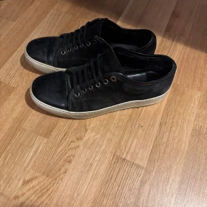 Svarta sneakers från Lanvin i skinn - Svarta sneakers från Lanvin i äkta skinn med klassisk rund tå och snörning. Skorna har vit sula och svarta skosnören, samt diskreta sömmar längs sidorna. Perfekta för dig som gillar stilrena och tidlösa sneakers med premiumkänsla. Priset är diskuterbart vid en snabb och enkel affär, skorna är i bra skick det ända är att liten del av sulan har trillat av som visas på bilderna 