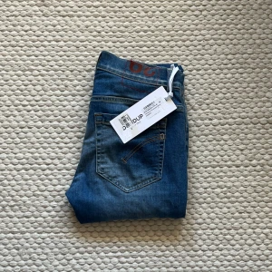 Blå jeans från Dondup - Snygga blå jeans från Dondup med klassisk femficksdesign och diskret tvättad look. Jeansen har raka ben och normal passform, perfekt för dig som gillar stilrena och tidlösa plagg. Materialet är mjukt denim och midjan är klassisk. Taggen sitter kvar.