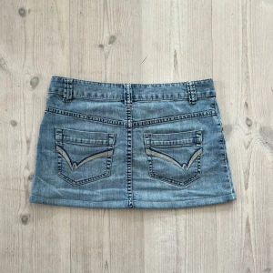 Blå lågmidjad jeanskjol  - Ljusblå lågmidjad jeanskjol från Flash Jeans i storlek 38. Tvärs över midjan är det 40 cm och den är 30 cm lång (längs med sidan). Fint skick. Använd gärna köp nu!