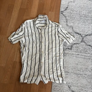 Randig kortärmad skjorta från Zara - Snygg vit skjorta från Zara med svarta vertikala ränder och klassisk krage.