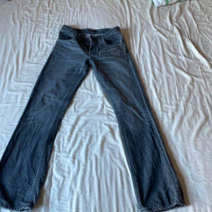 Blå jeans från Nudie Jeans Co bootcut - Snygga blå jeans från Nudie Jeans Co med klassisk femficksdesign och coola detaljer på bakfickorna. Modellen har bootcut-ben och normal passform, tillverkade i slitstarkt jeanstyg. Perfekta för dig som gillar en avslappnad och tidlös stil.