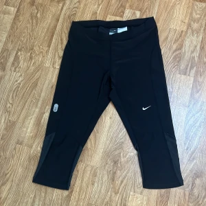 Svarta Nike Dri-Fit träningstights - Svarta träningstights från Nike med Dri-Fit-teknologi. De har en croppad längd (trekvarts) och meshpaneler vid vaden för extra ventilation. Storlek S men upplever snarare som M. Använda fåtal gånger.