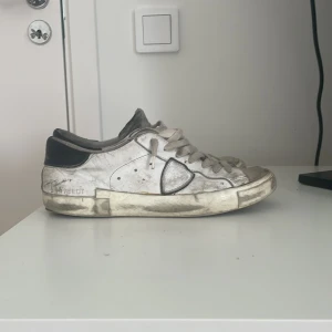 Vita sneakers med svarta detaljer - Säljer ett par Philippe model inget fel på förutom att dom är riktigt skitiga och har ett lite hål back på Sulan men d är inget märkvärdigt och det kommer inte in vattten eller något under där/ kan tväta innan innan jag fraktar/ kan tänka mig och mötas upp storlek 