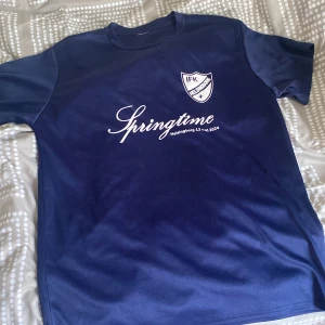 Blå t-shirt med tryck från Springtime - Säljer en blå t-shirt med tryck från Springtime Helsingborg. T-shirten har korta ärmar och ett tryck med texten 'Springtime' och datumet 13 maj 2024 på framsidan. Baksidan har flera logotyper, inklusive Helsingborg och Ramlösa. Perfekt för löpare eller som minne från evenemanget.