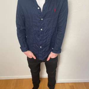 Ralph Lauren skjorta - Tja säljer en stilren Ralph lauren skjorta i färgen marinblå. Som är perfekt till sommarn eller till allmänt festliga tillfällen. Storlek, 14-16 i barn storlek alltså XS i herr storlek. Nypris 1200kr. Änvänd max 5 gånger så skjortan är i väldigt bra skick i princip som ny om man stryker den, köpt på Ralph Laurens egna hemsida. Hör av er vi minsta lilla fråga eller fundering:) Modellen på bilden är cirka 165cm lång! 