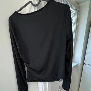 Svart långärmad topp - Snygg svart långärmad topp med enkel design. Perfekt för en stilren look. Passar bra till både jeans och kjol.