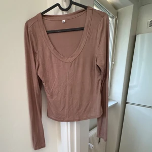 Brun långärmad topp - Säljer en stilren beige långärmad topp med v-ringning. Perfekt för en avslappnad look. Passar bra till jeans eller kjol. Hör av dig vid intresse!