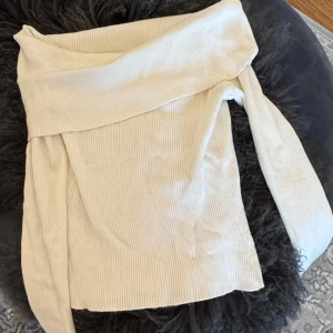 Vit ribbad offshoulder topp från H&M - Säljer en stilren vit ribbad offshoulder topp från H&M. Perfekt för en trendig look med sin unika design och bekväma passform. Passar utmärkt till både jeans och kjol. Hör av dig vid intresse!