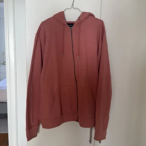 Rosa hoodie från lager 157 - Säljer en snygg rosafärgad hoodie från Lager 157. Den har dragkedja och en klassisk huva med snören. Perfekt för en avslappnad stil.