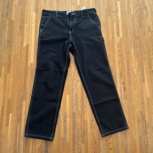 Cargo jeans från Pull&Bear - Säljer ett par svarta cargobyxor med vit sömm. Stl 42. 