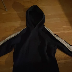 Mörkblå hoodie från GANT - Säljer en snygg mörkblå hoodie från GANT med vita ränder längs ärmarna. Perfekt för en avslappnad stil. Den har en klassisk huva och långa ärmar.                                                              Den är storlek M men passar bra som storlek S.    Skriv vid minsta fråga!