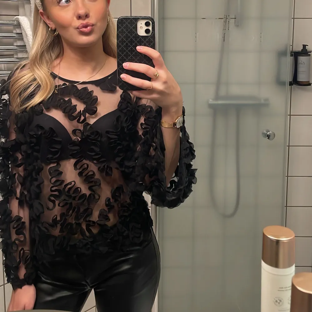 Snygg svart blus med genomskinligt tyg och blommiga detaljer. Perfekt för en kväll ute eller en speciell tillställning. 💓😊. Puserot.