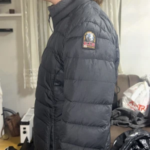 Svart dunjacka från Parajumpers - Säljer en svart dunjacka från Parajumpers. Jackan är superlätt och har en dragkedja framtill. Den har en hög krage och ett märke på ärmen. Perfekt för kyliga dagar!