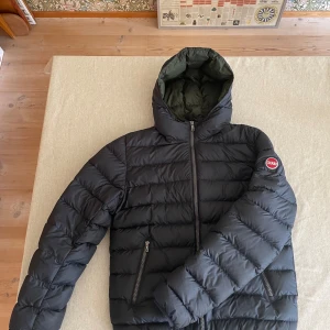 Svart pufferjacka från Colmar - Säljer en svart pufferjacka från Colmar med dragkedja och huva. Jackan har en quiltad design och är perfekt för hösten/vintern, säljer billigt för behöver pengar. Tveka inte om att höra av er om någon fråga! Små tecken på användning men inget man ser tydligt 