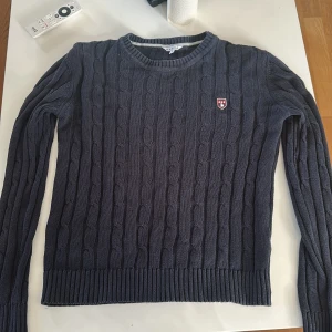 Mörkblå stickad tröja från Marine - Säljer en snygg mörkblå stickad tröja från Marine med kabelstickat mönster. Tröjan har långa ärmar och en rund halsringning. Perfekt för kyligare dagar! Inga defekter alls.! Använd fåtal gånger😀