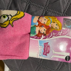 Strumpbyxor Disney Princess-motiv - Säljer ett par rosa strumpbyxor motiv av Disney Princess. Strumporna har en härlig rosa färg och är dekorerade med en prinsessdesign som gör dem extra speciella för alla Disney-fans.