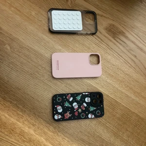Tre mobilskal - Säljer tre olika mobilskal. Ett transparent skal med vita bubblor, ett rosa skal från Ideal of Sweden och ett svart skal med julmotiv av snögubbar och granar. Perfekt för att ge din mobil en ny look!
