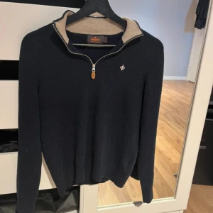 Mörkblå merinoulltröja från Morris - Säljer en stilren mörkblå tröja från Morris i 100% merinoull. Tröjan har en dragkedja vid halsen och en liten broderad detalj på bröstet. Tröjan är storlek S men passar även dig med storlek xs.